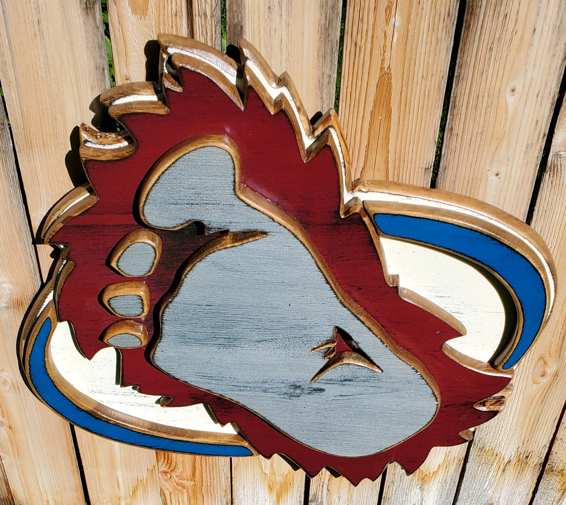 Wooden cutout of a bigfoot logo displayed on a wooden fence