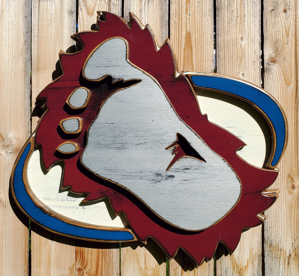 Wooden cutout of a bigfoot logo displayed on a wooden fence