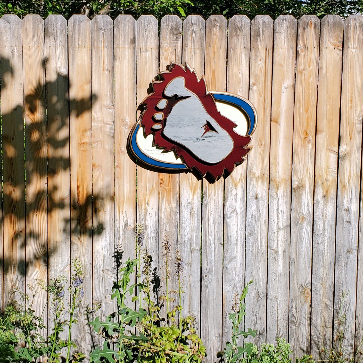 Wooden cutout of a bigfoot logo displayed on a wooden fence