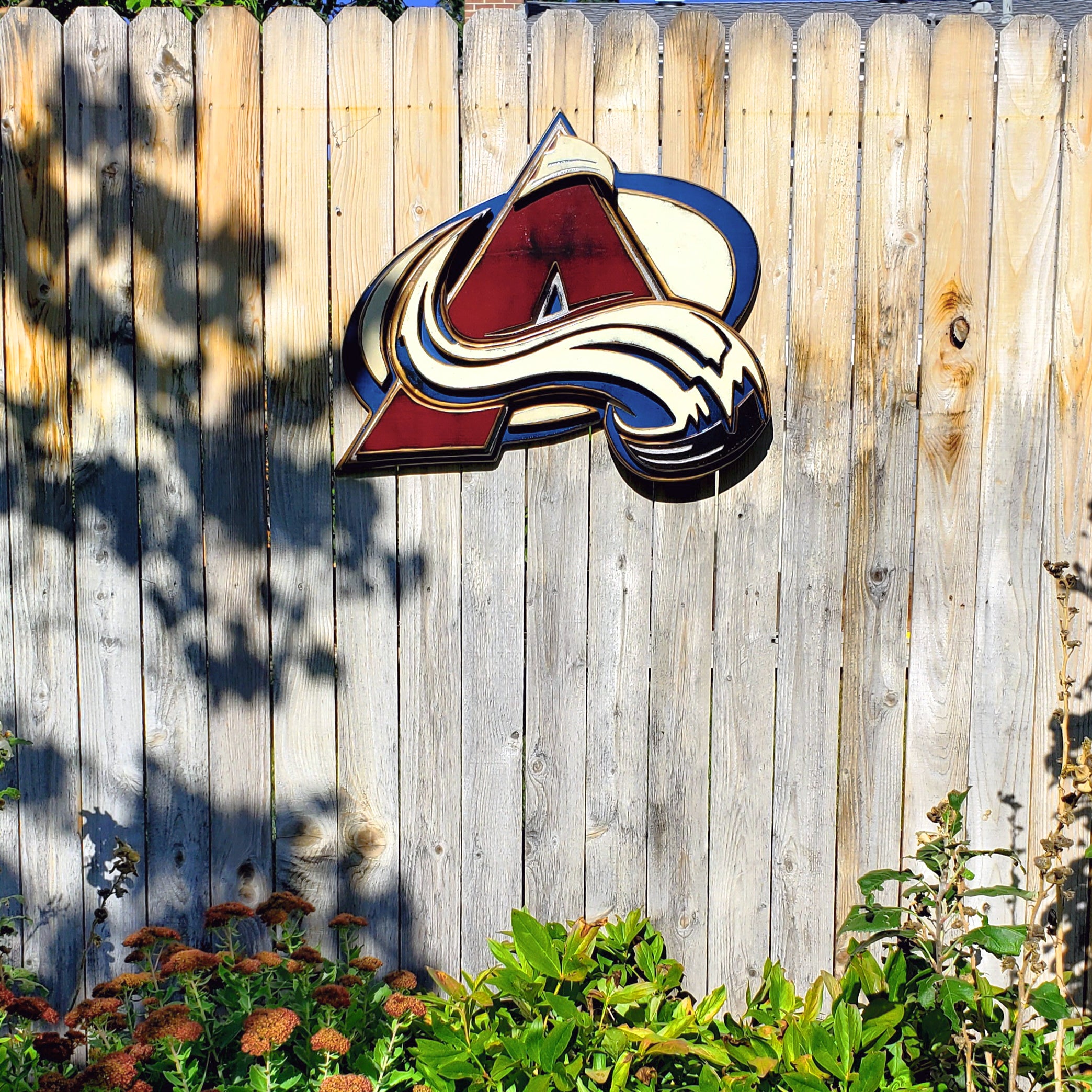 Colorful Avalanche A logo with abstract design hanging from a wooden fence