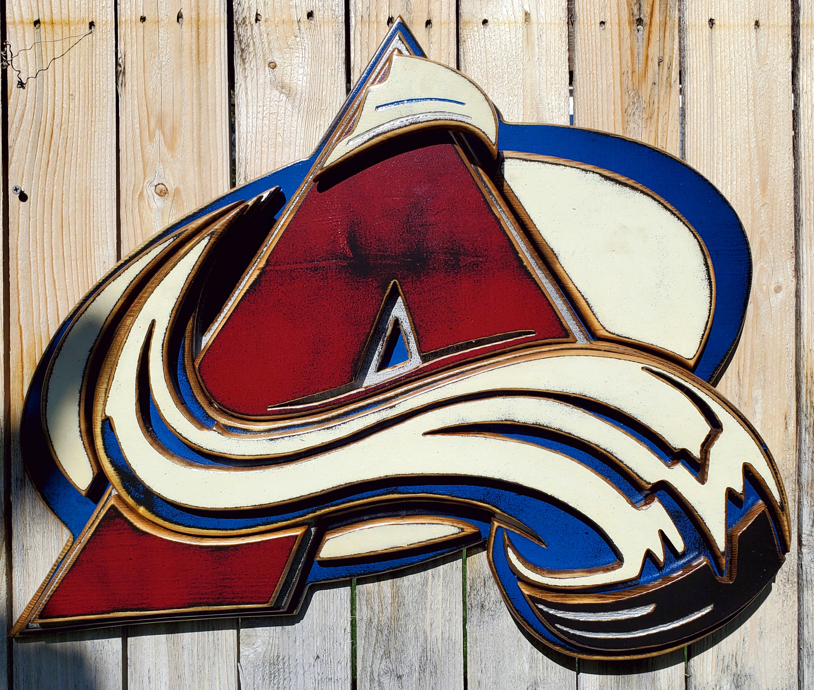 Colorful Avalanche A logo with abstract design hanging from a wooden fence