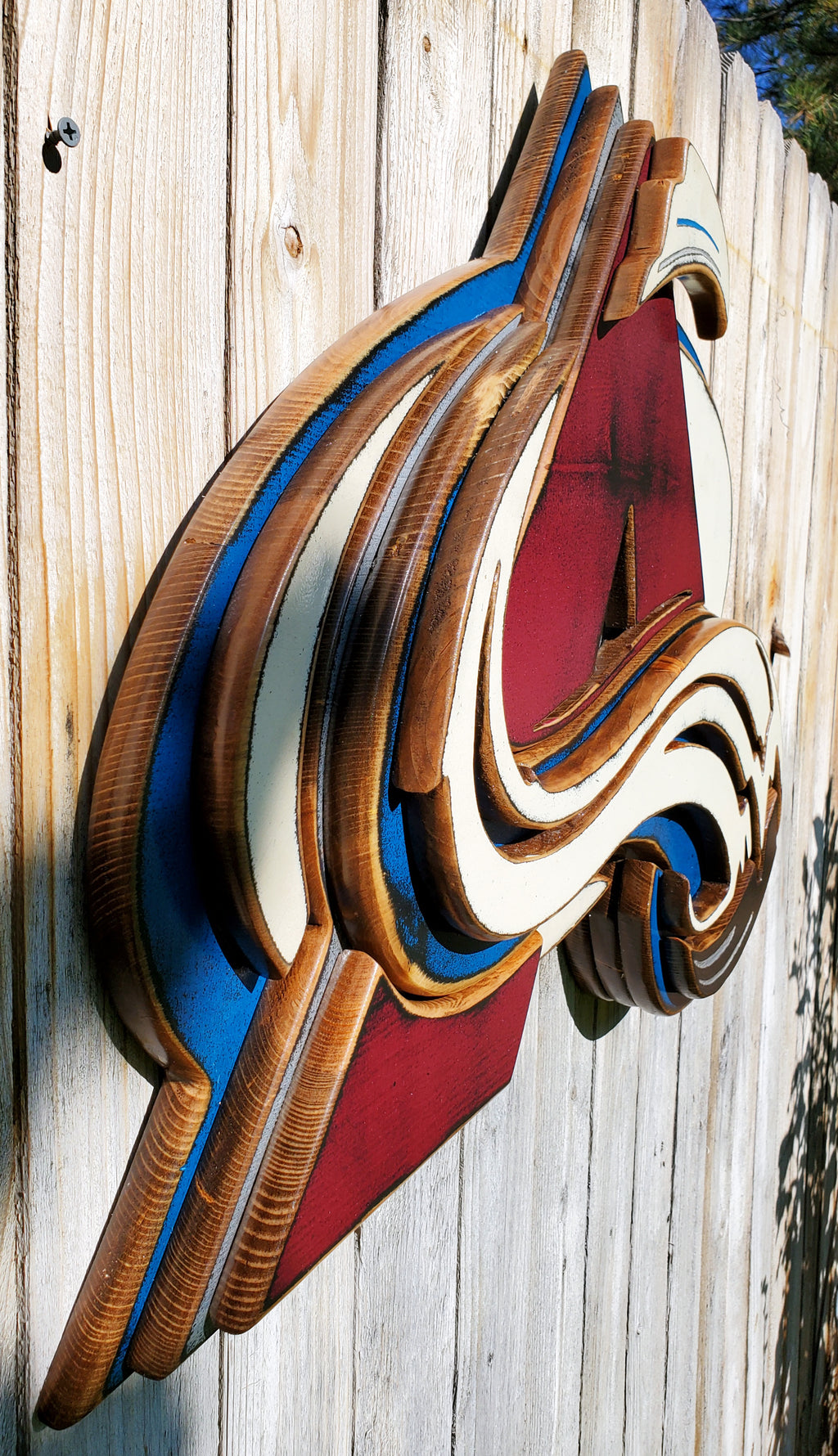 Colorful Avalanche A logo with abstract design hanging from a wooden fence