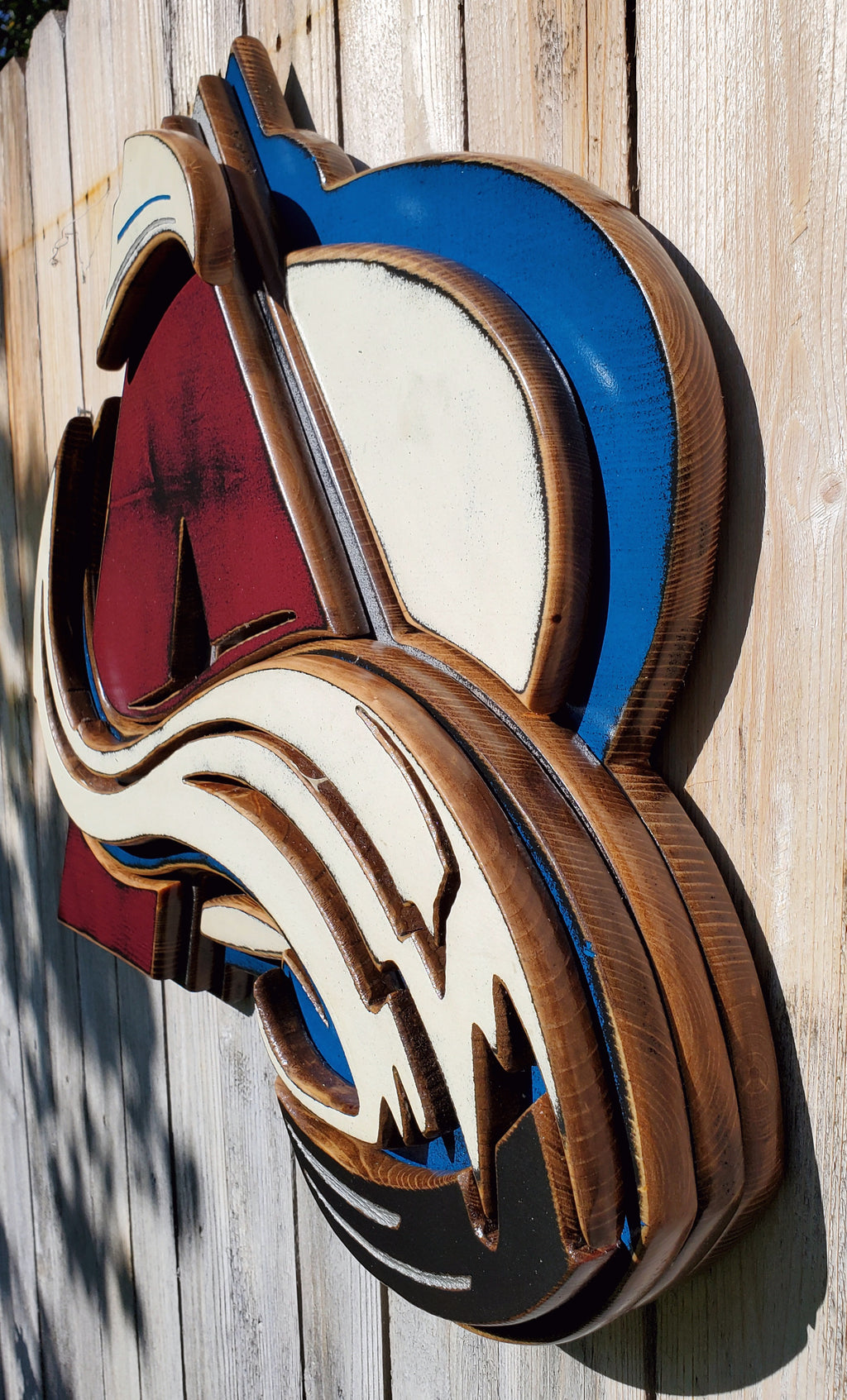 Colorful Avalanche A logo with abstract design hanging from a wooden fence