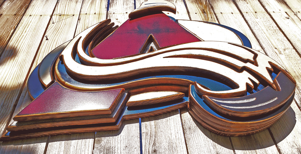 Colorful Avalanche A logo with abstract design hanging from a wooden fence