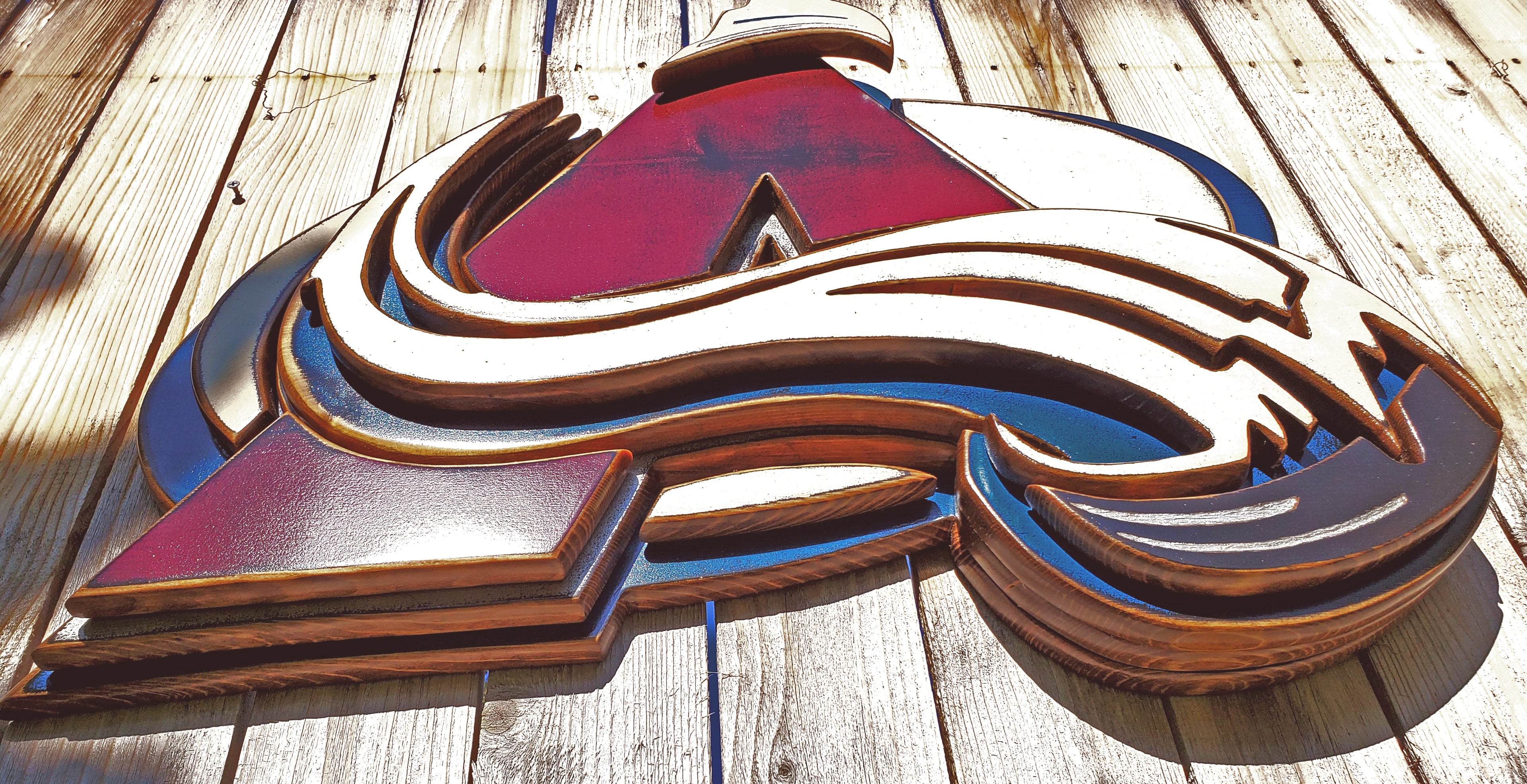 Colorful Avalanche A logo with abstract design hanging from a wooden fence