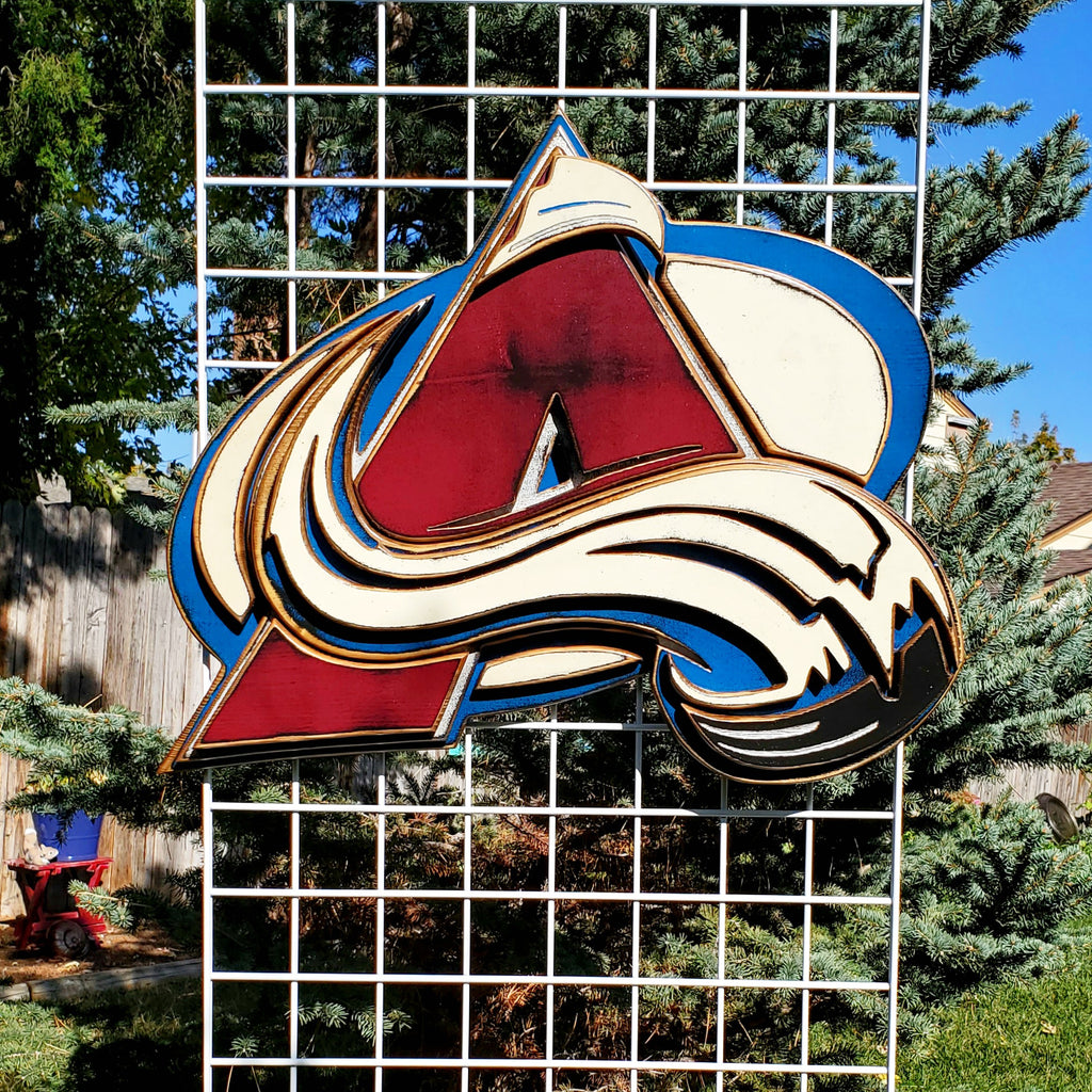 Colorful logo with abstract design hanging from of a metal lattice and trees