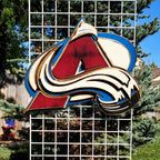 Colorful logo with abstract design hanging from of a metal lattice and trees