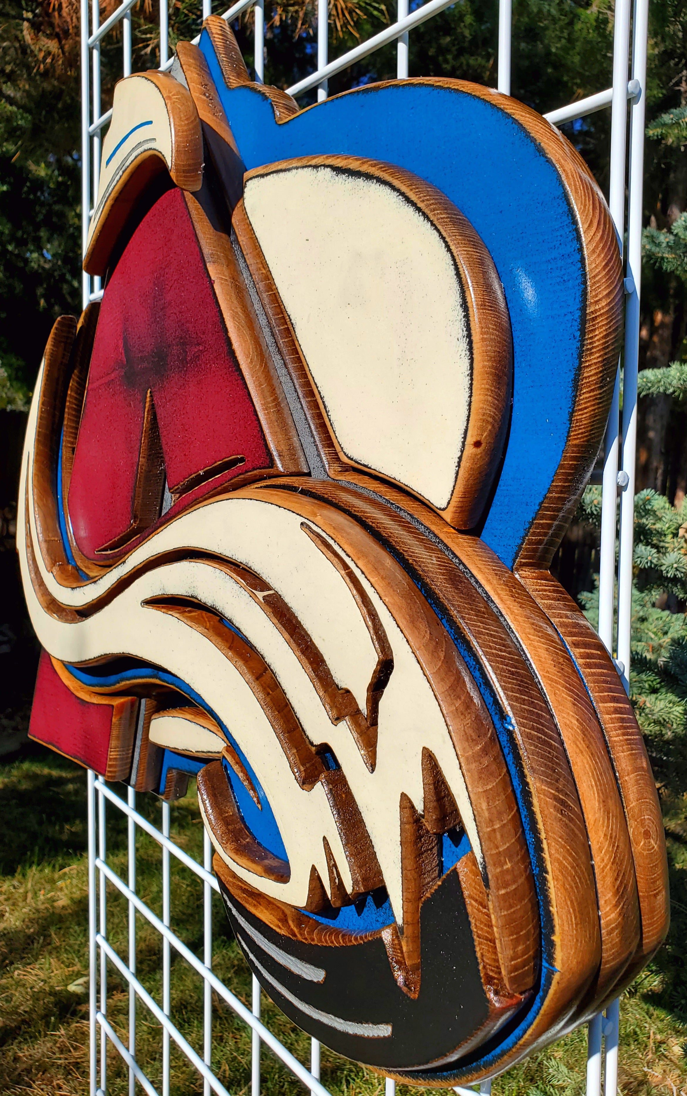 Colorful logo with abstract design hanging from of a metal lattice and trees