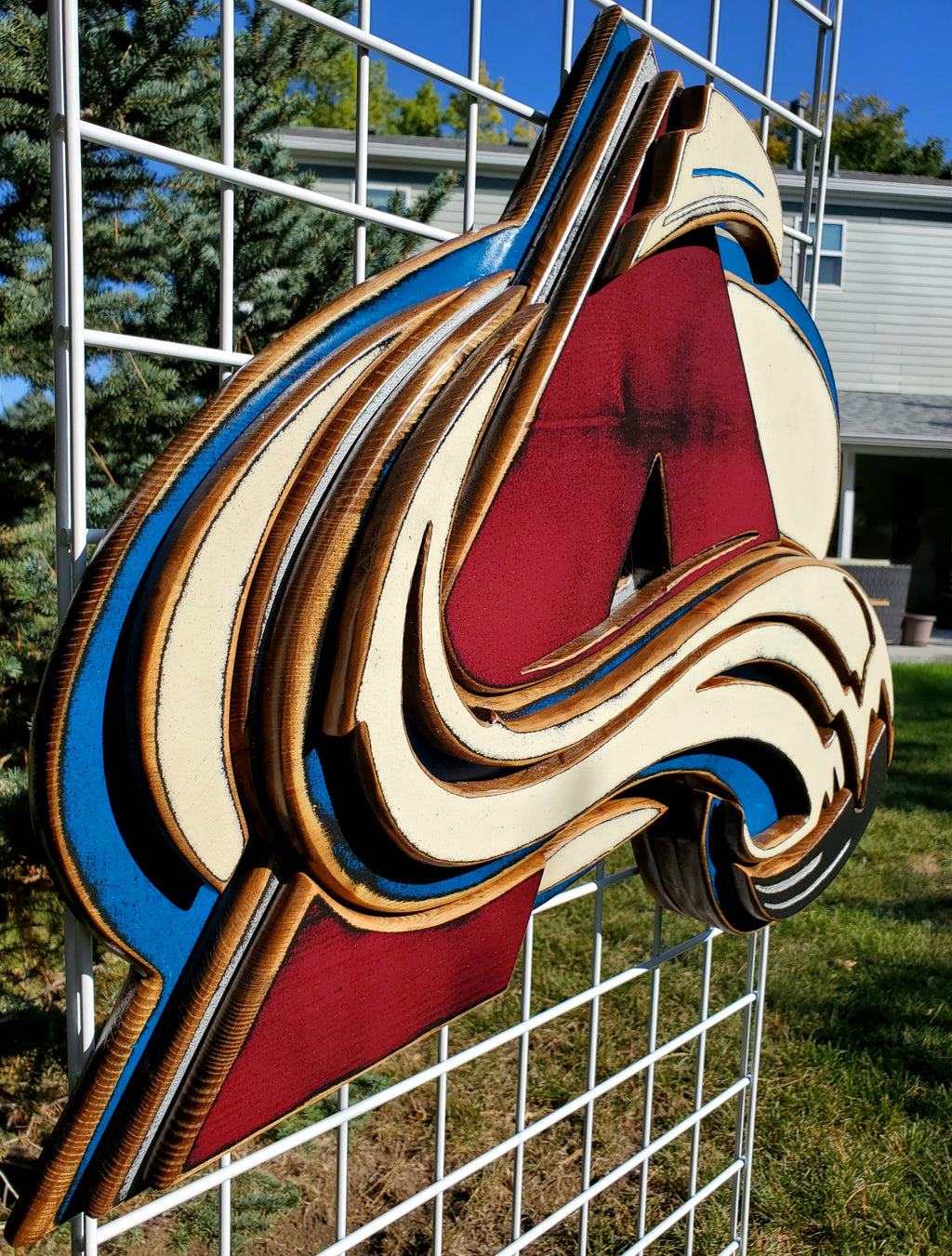 Colorful logo with abstract design hanging from of a metal lattice and trees