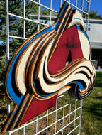 Colorful logo with abstract design hanging from of a metal lattice and trees