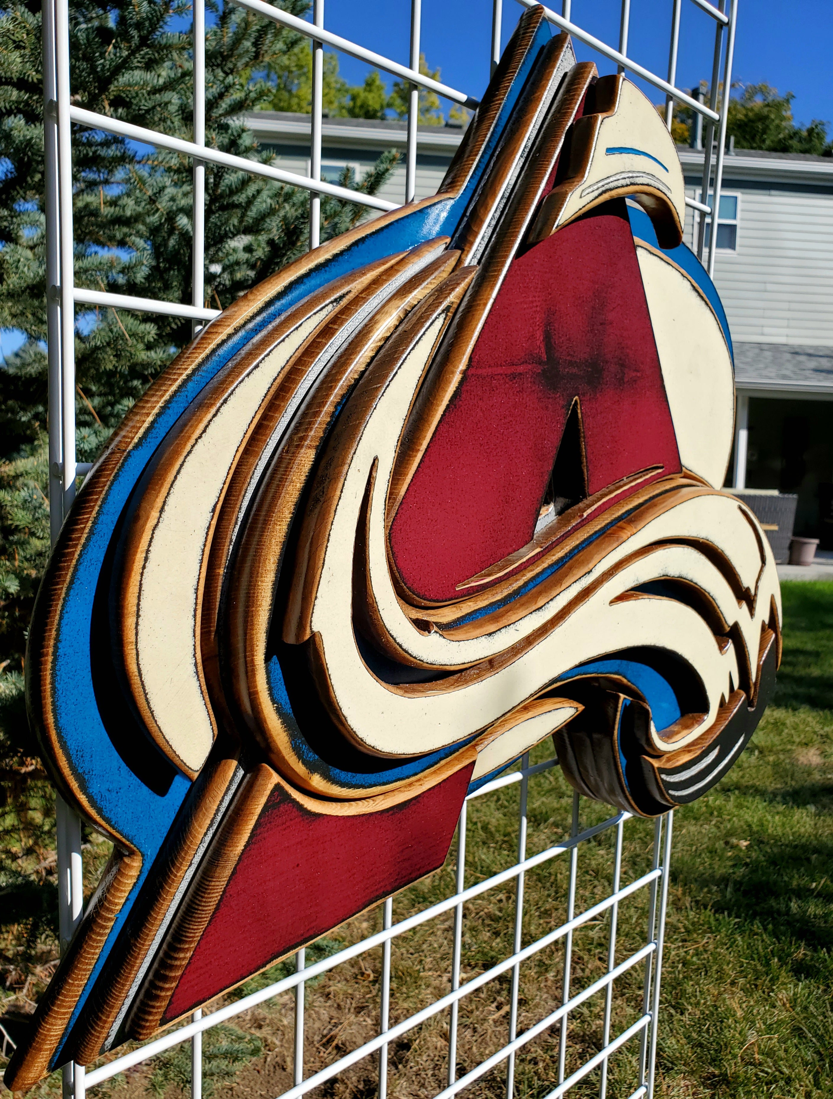 Colorful logo with abstract design hanging from of a metal lattice and trees