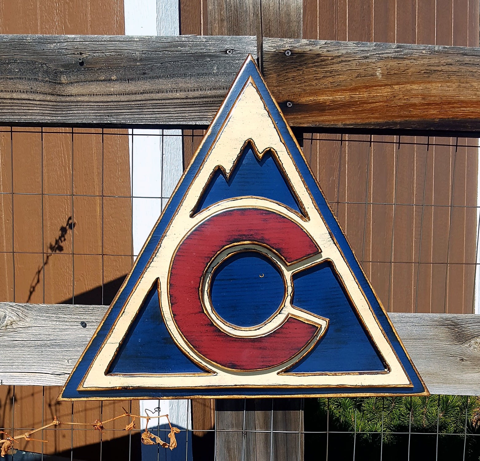 Colorful Avalanche triangle logo displayed on a metal lattice and wood fence