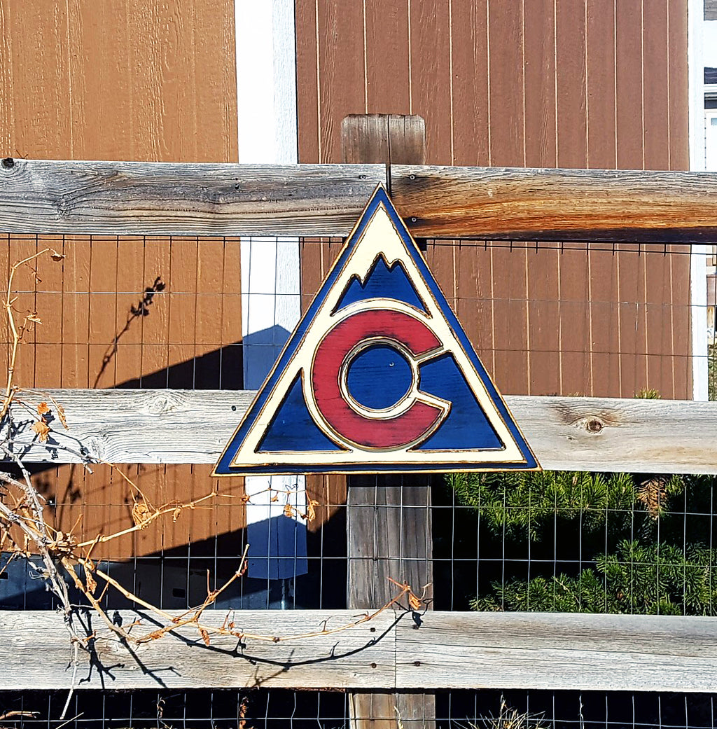 Colorful Avalanche triangle logo displayed on a metal lattice and wood fence