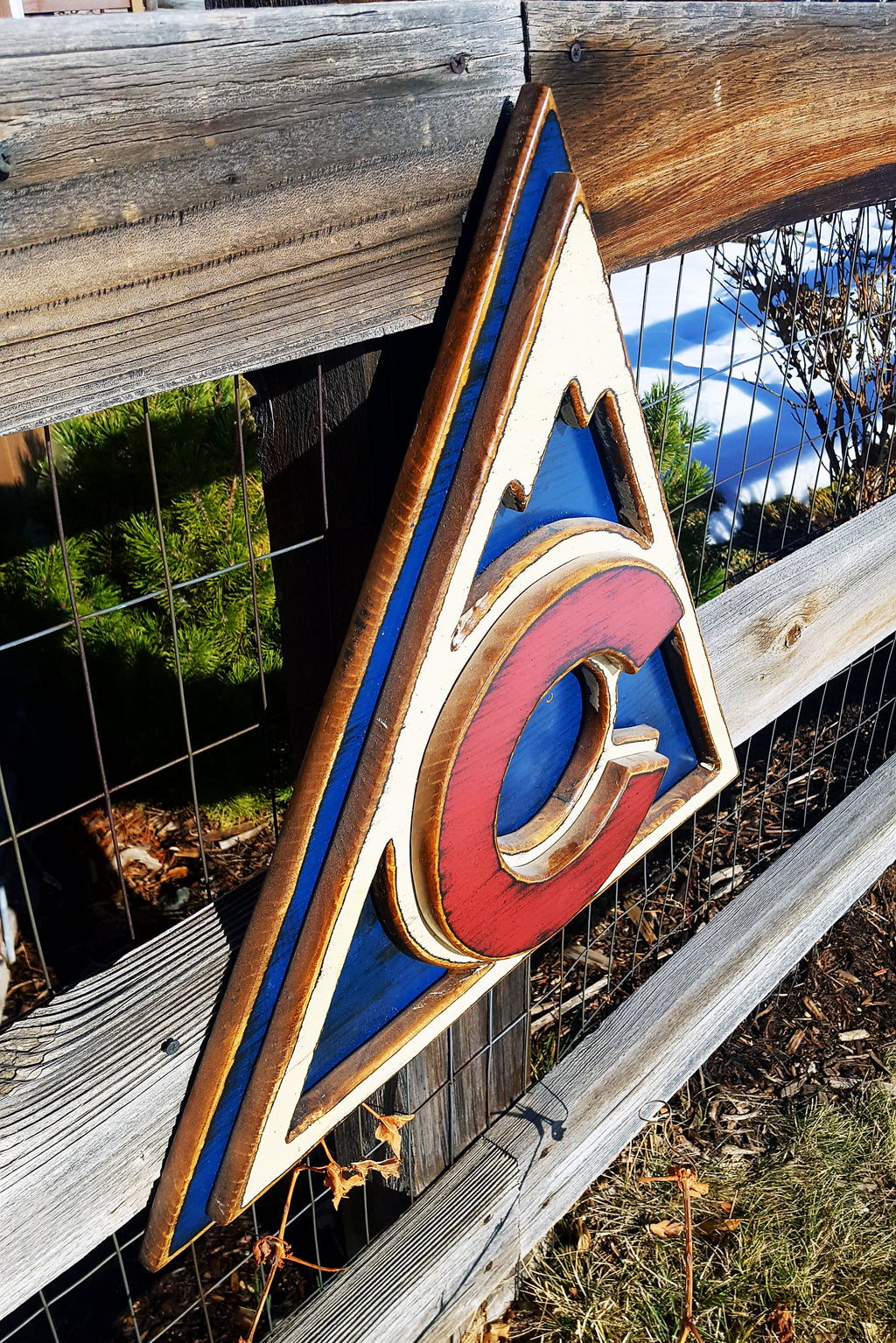 Colorful Avalanche triangle logo displayed on a metal lattice and wood fence