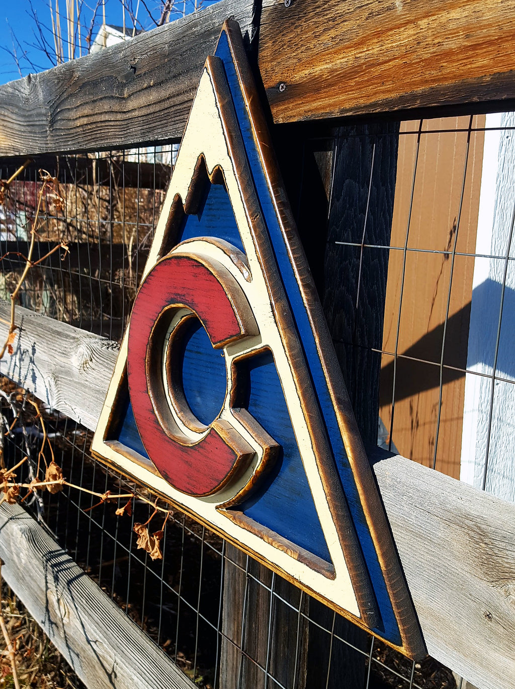 Colorful Avalanche triangle logo displayed on a metal lattice and wood fence