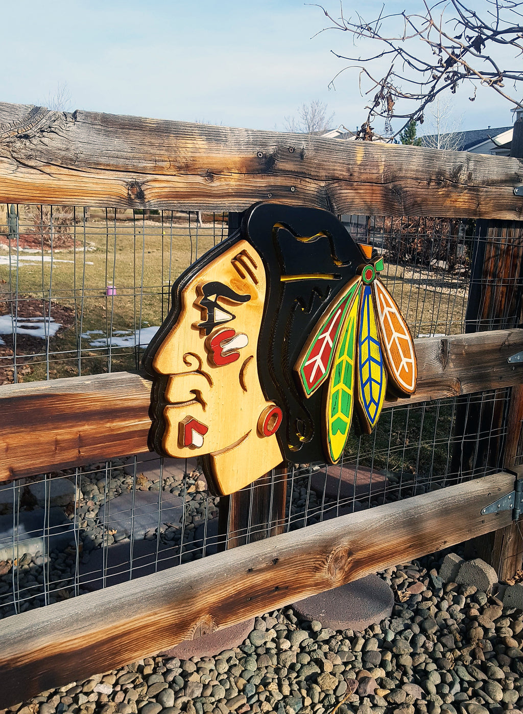Decorative wooden Native American with colorful feather design on a wooden fence