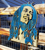 Wooden sculpture of Bob Marley's face and hair in blue and brown tones on a wooden background
