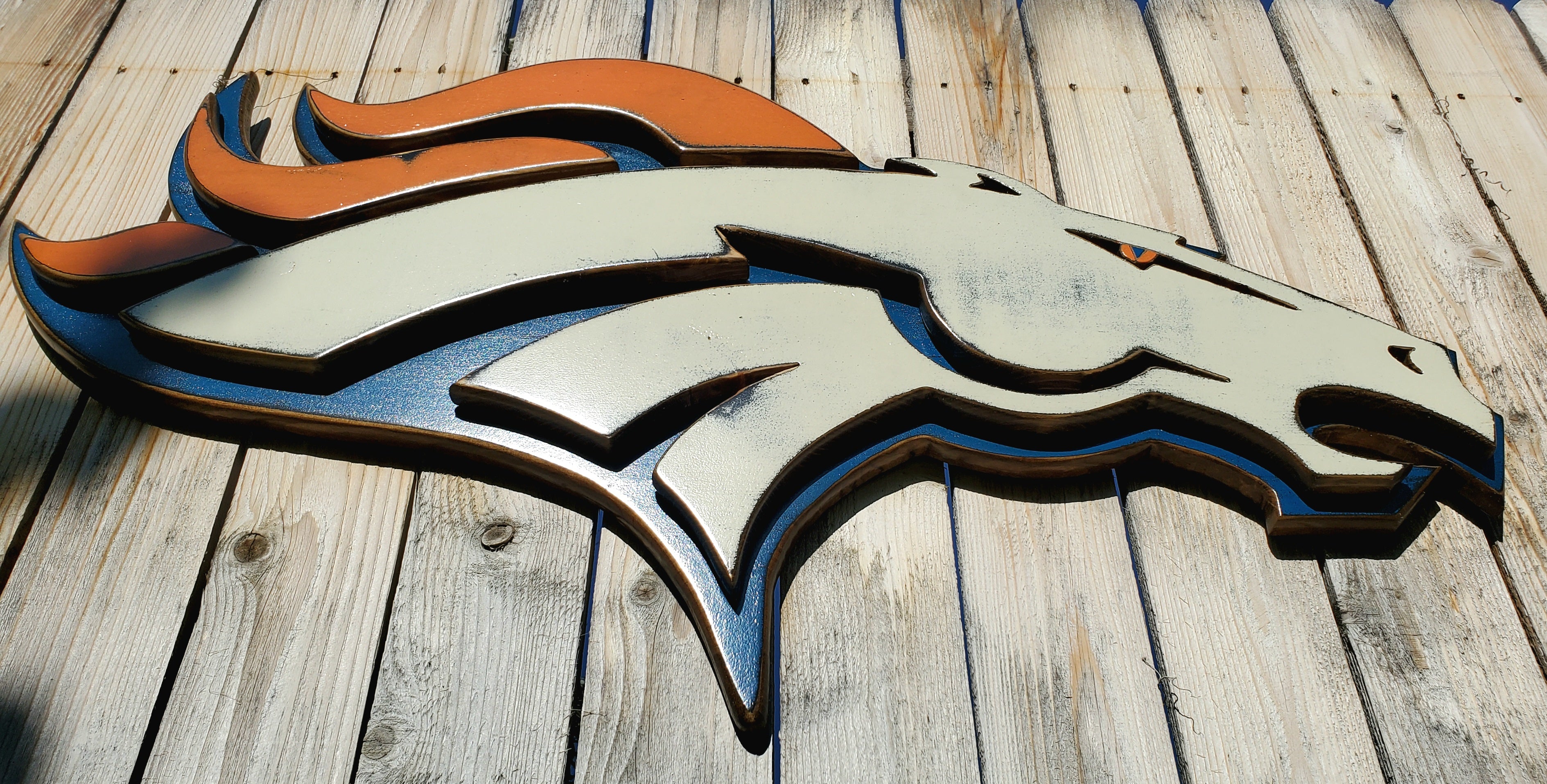 Denver Broncos modern logo displayed on a wooden fence