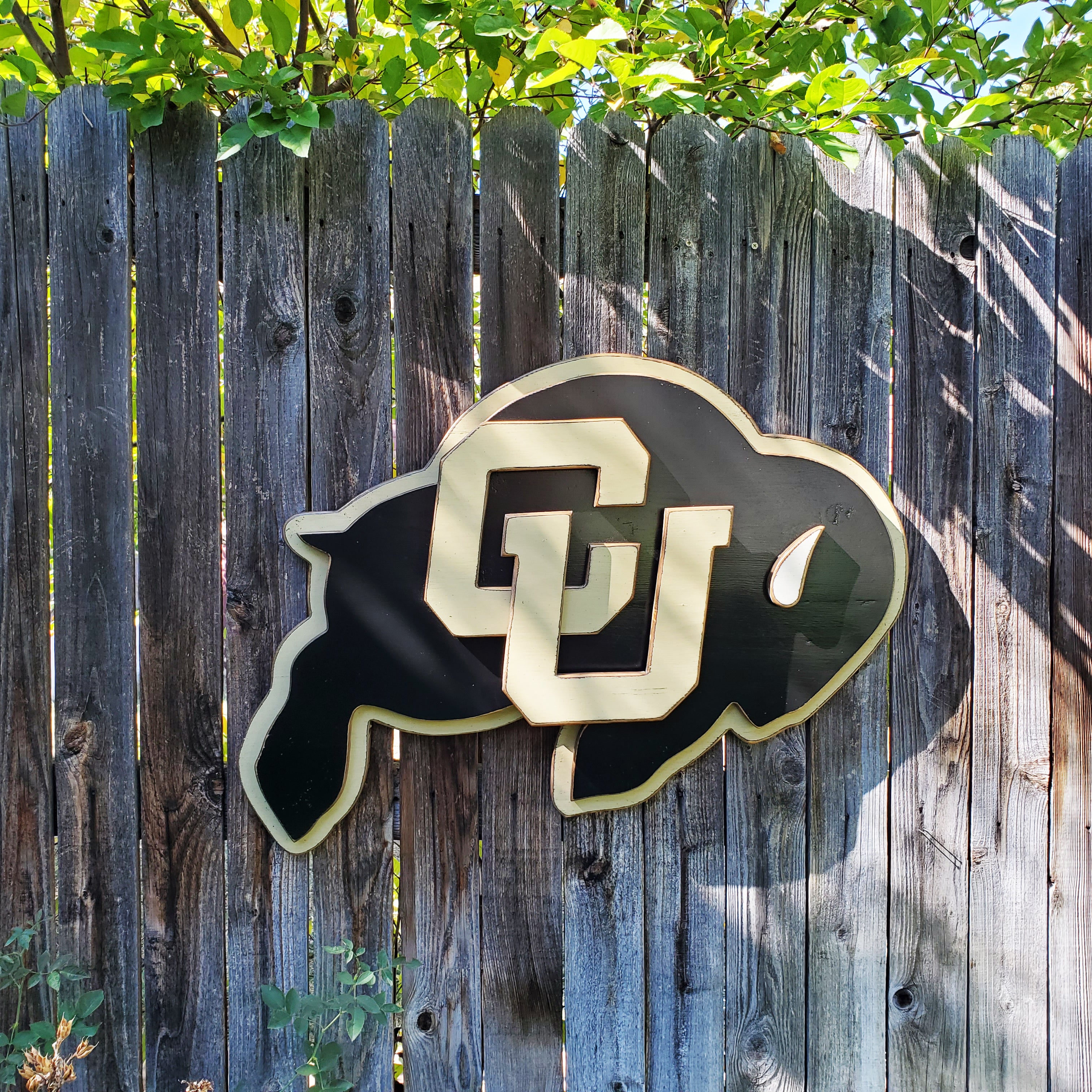 Wooden CU Buffs logo hanging on a wooden fence