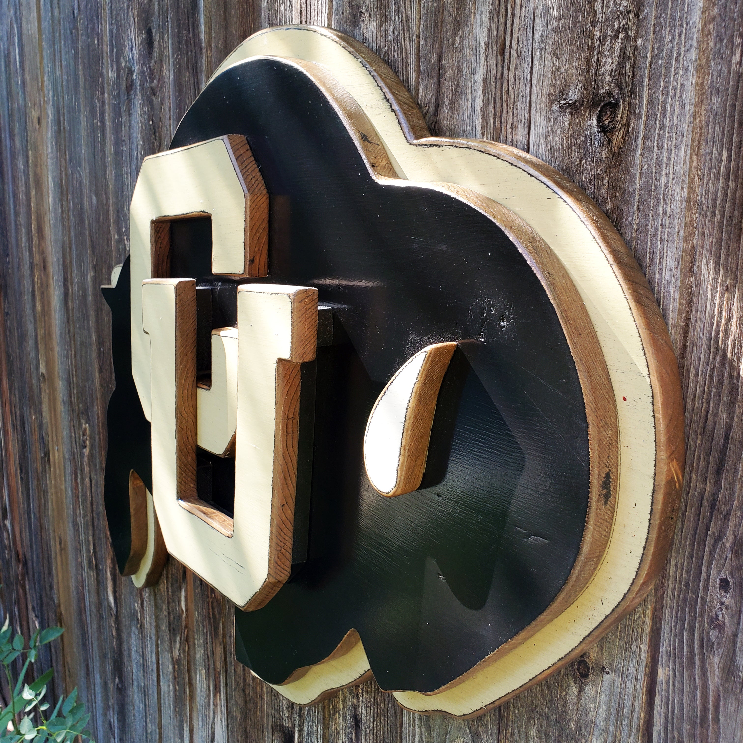 Wooden CU Buffs logo hanging on a wooden fence