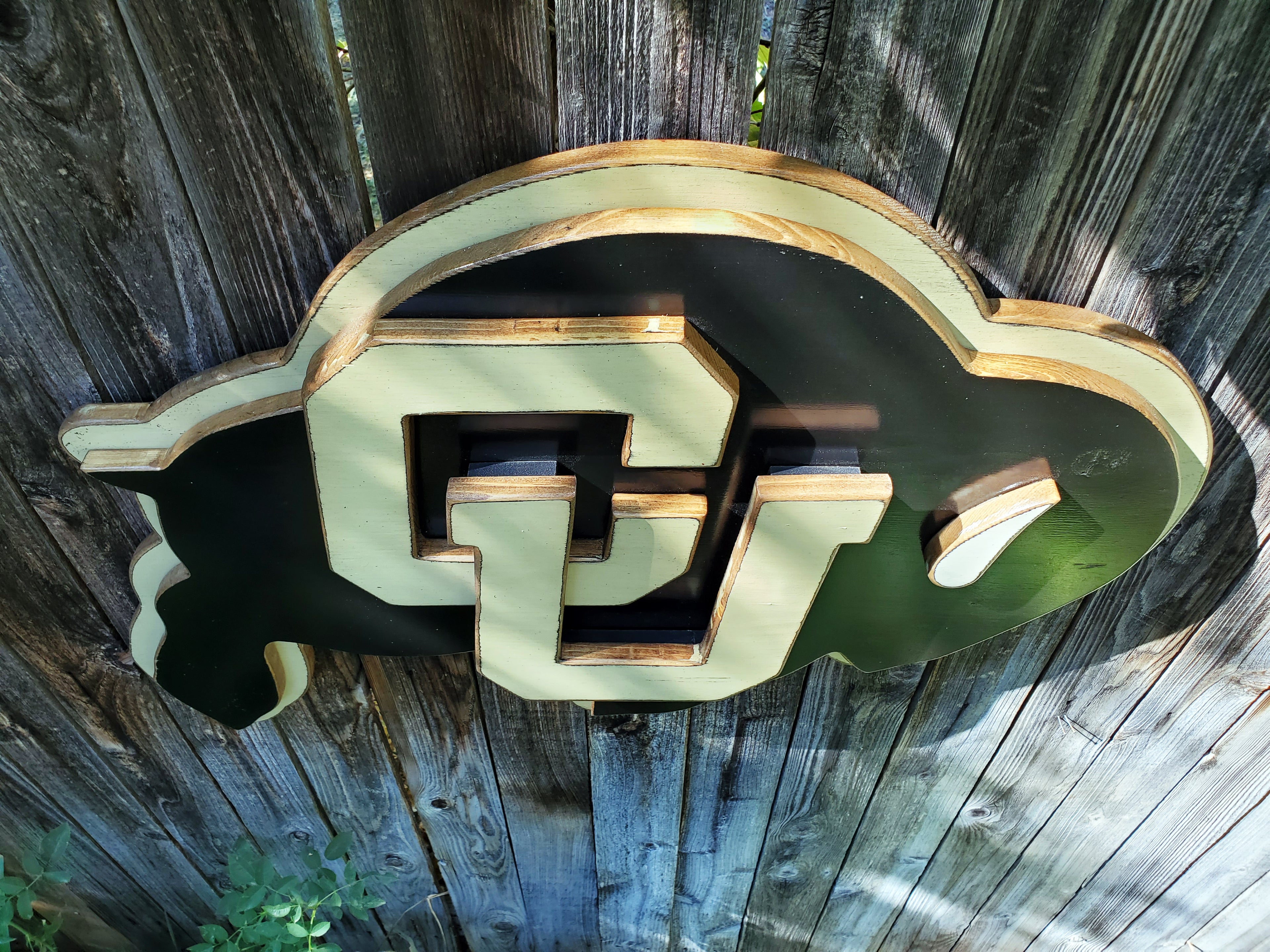 Wooden CU Buffs logo hanging on a wooden fence