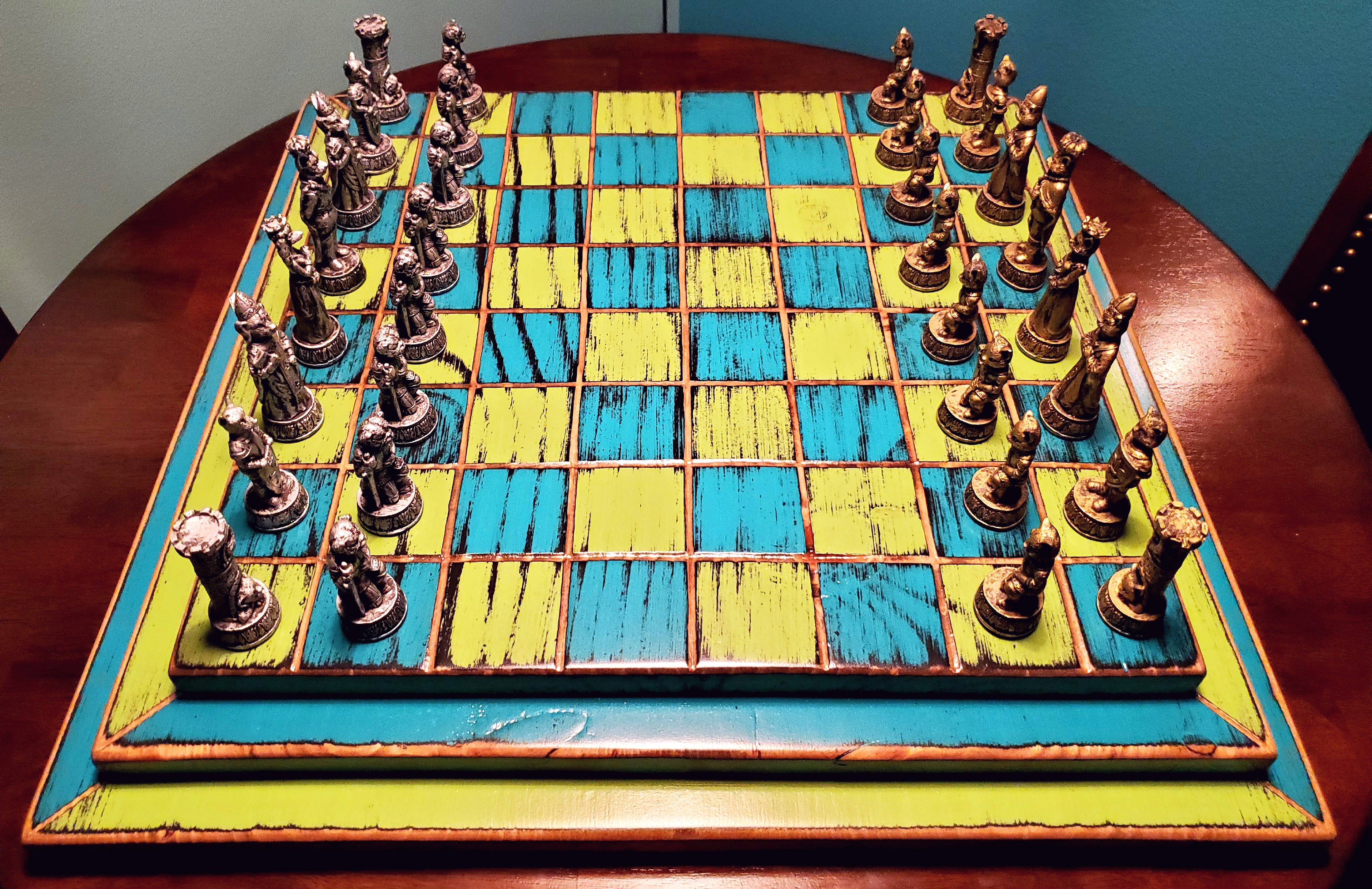 Colorful blue and yellow wooden chessboard with pieces on a round wooden table