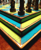 Close-up of a colorful blue and yellow wooden chessboard with chess pieces.