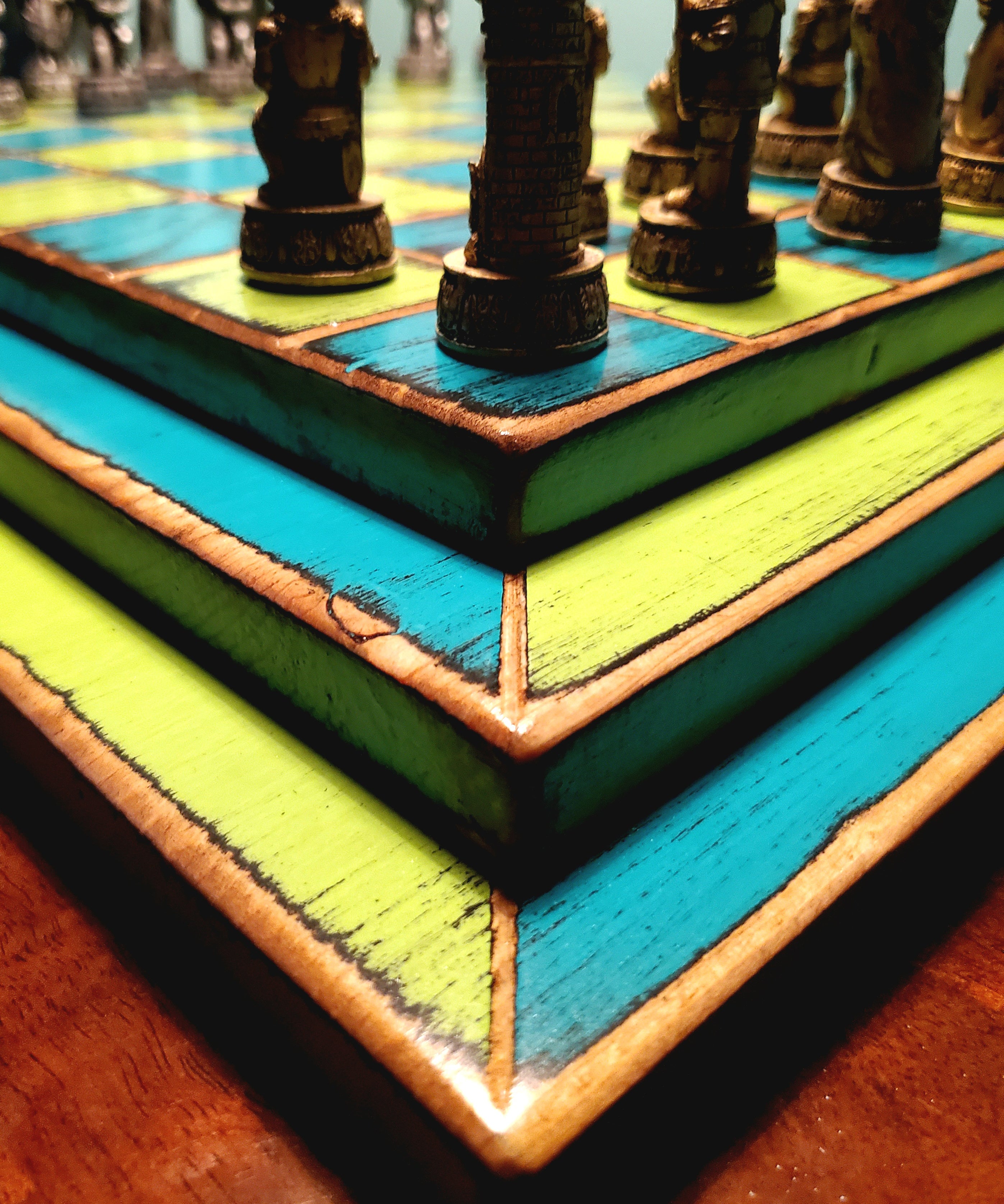 Close-up of a colorful blue and yellow wooden chessboard with chess pieces.