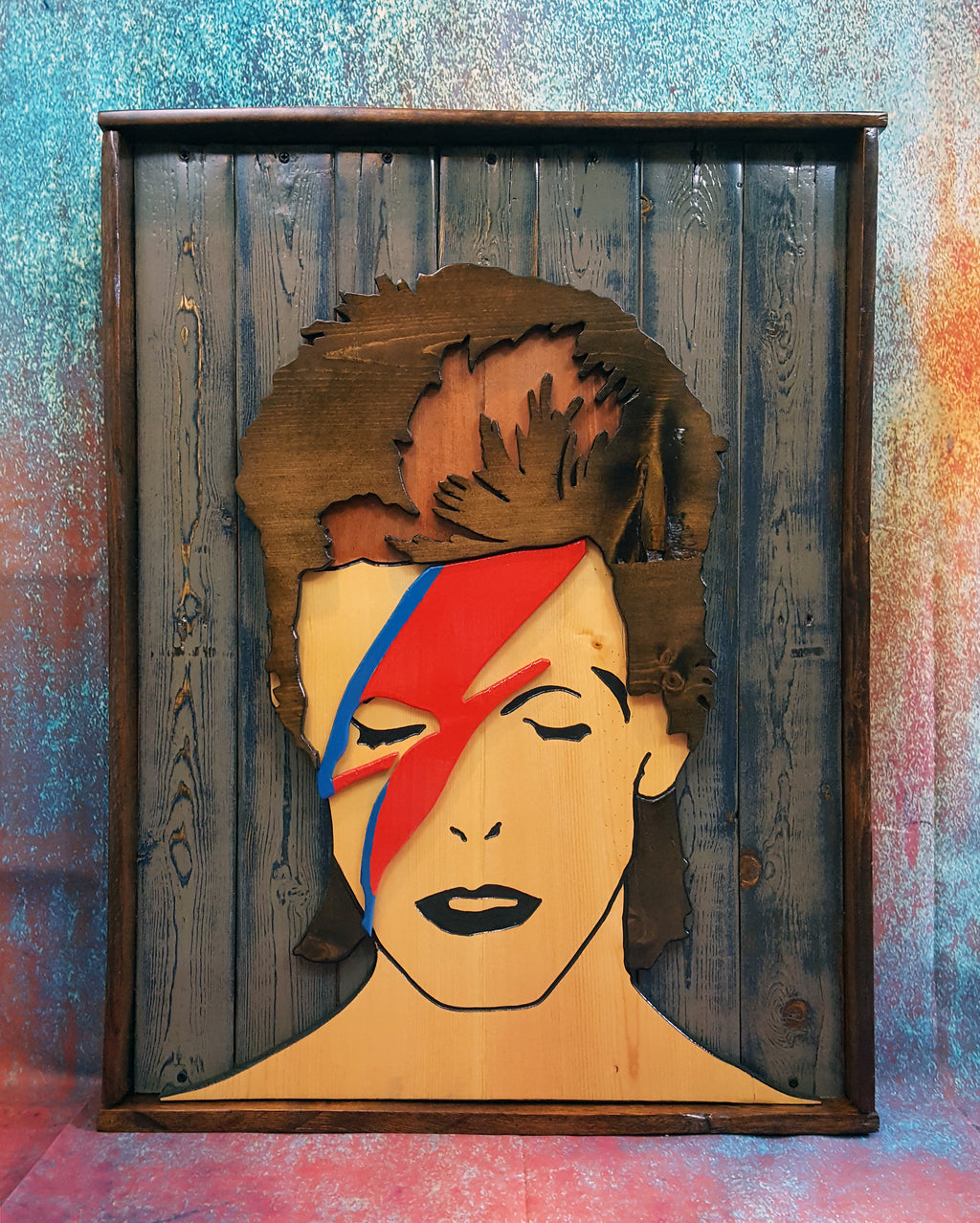 Wooden wall art of David Bowie's Aladdin Sane album cover photographed on a colorful backdrop