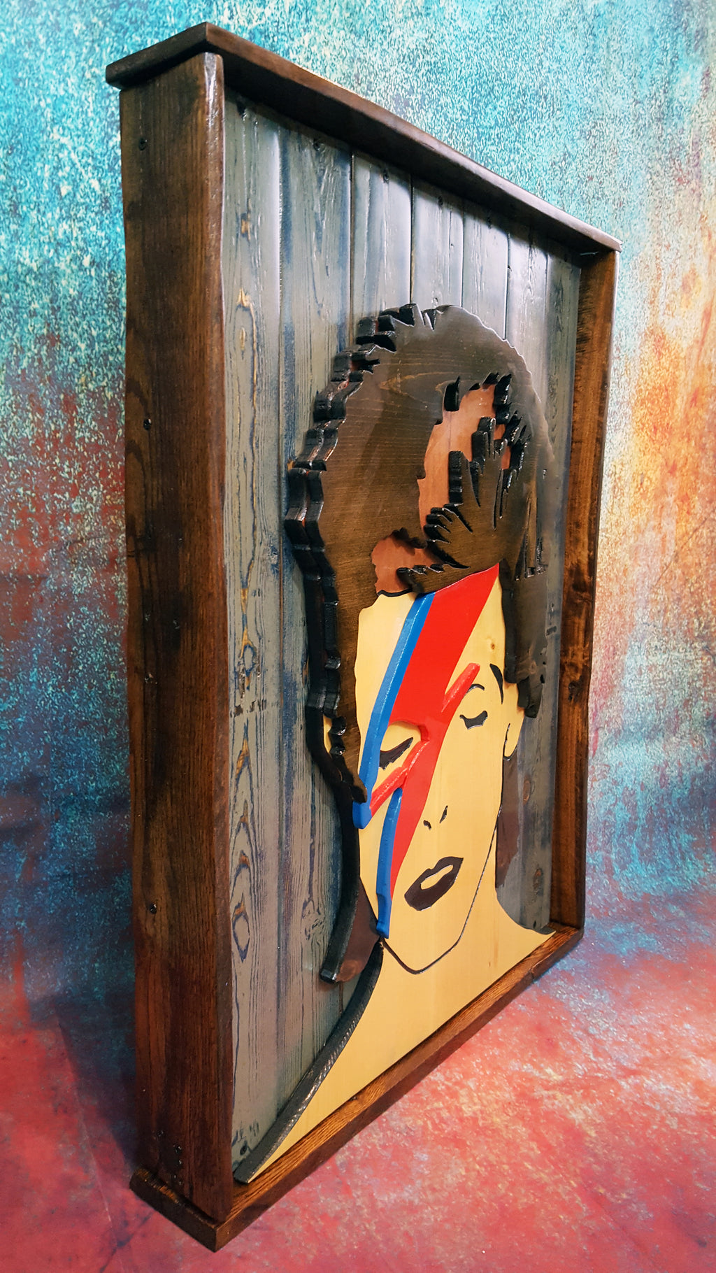 Wooden wall art of David Bowie's Aladdin Sane album cover photographed on a colorful backdrop