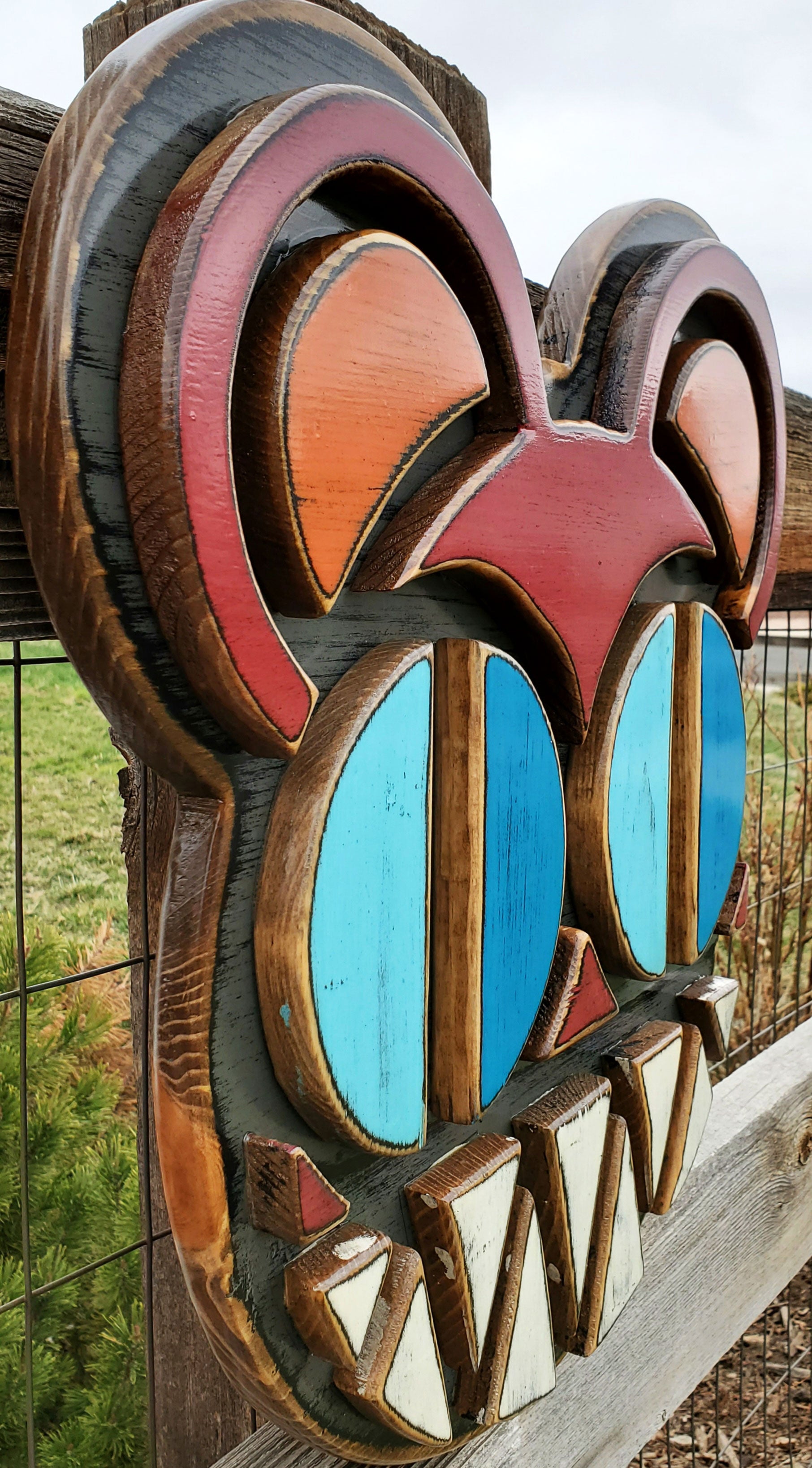 Decorative wooden wall art featuring Radiohead's Modified Bear logo on a wooden fence outdoors.
