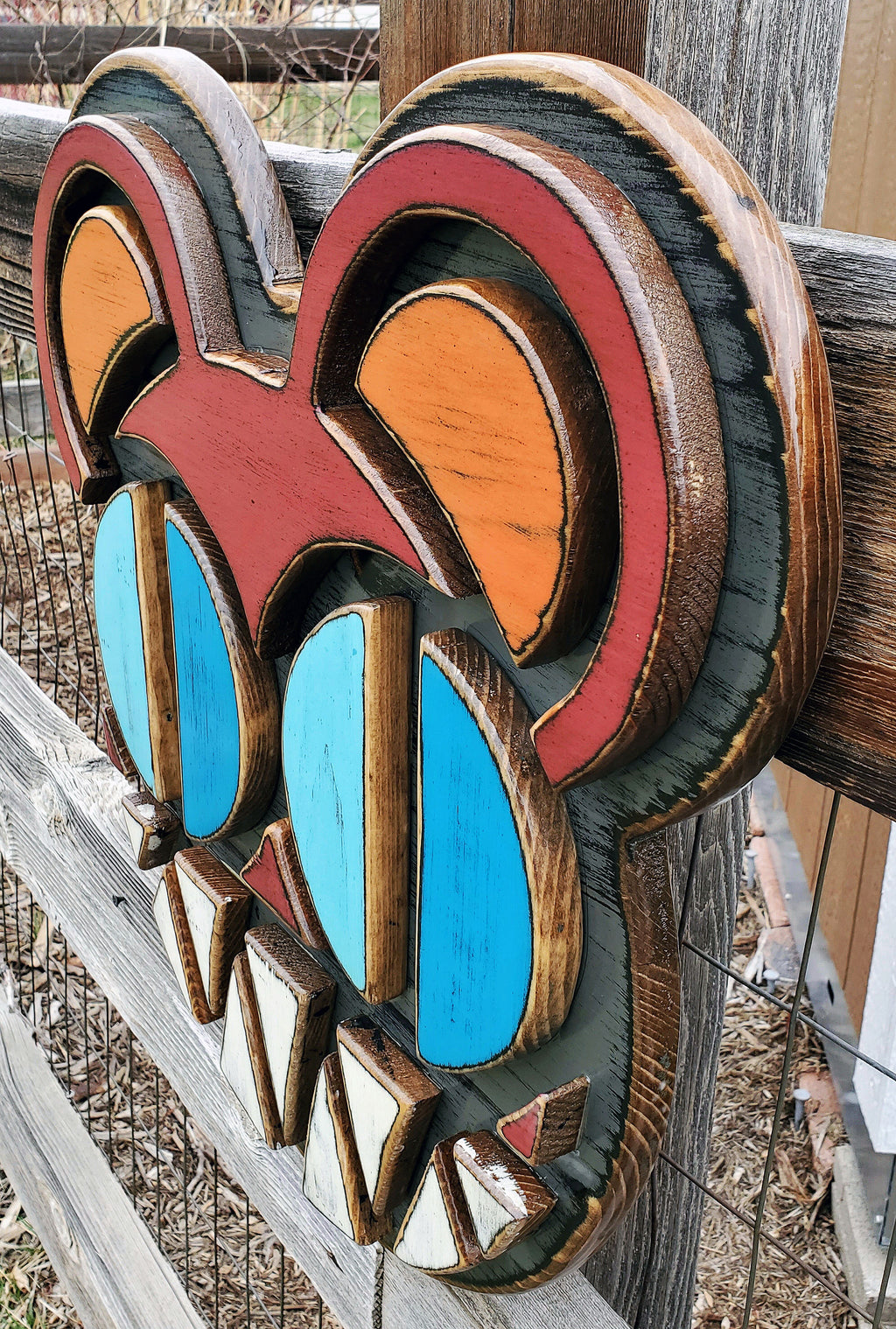 Decorative wooden wall art featuring Radiohead's Modified Bear logo on a wooden fence outdoors.