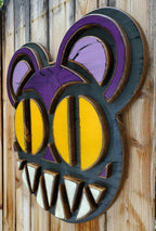 Decorative wooden wall art featuring Radiohead's Modified Bear logo on a wooden fence outdoors.