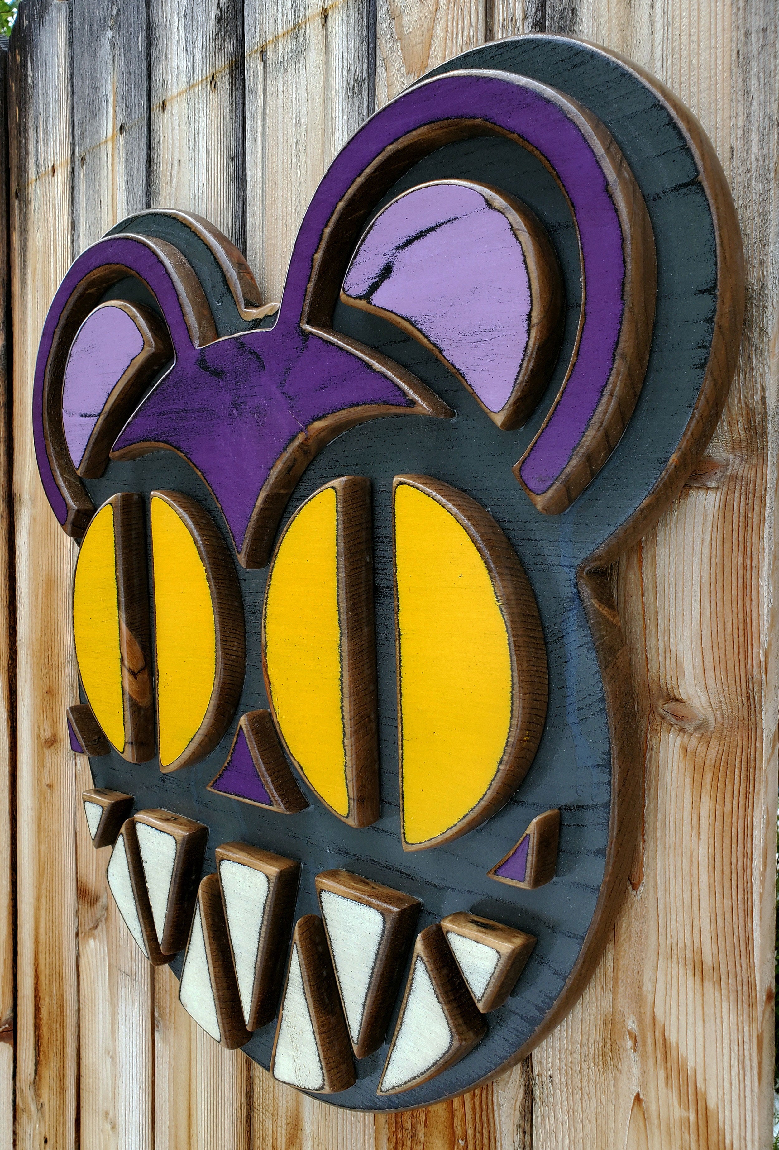 Decorative wooden wall art featuring Radiohead's Modified Bear logo on a wooden fence outdoors.