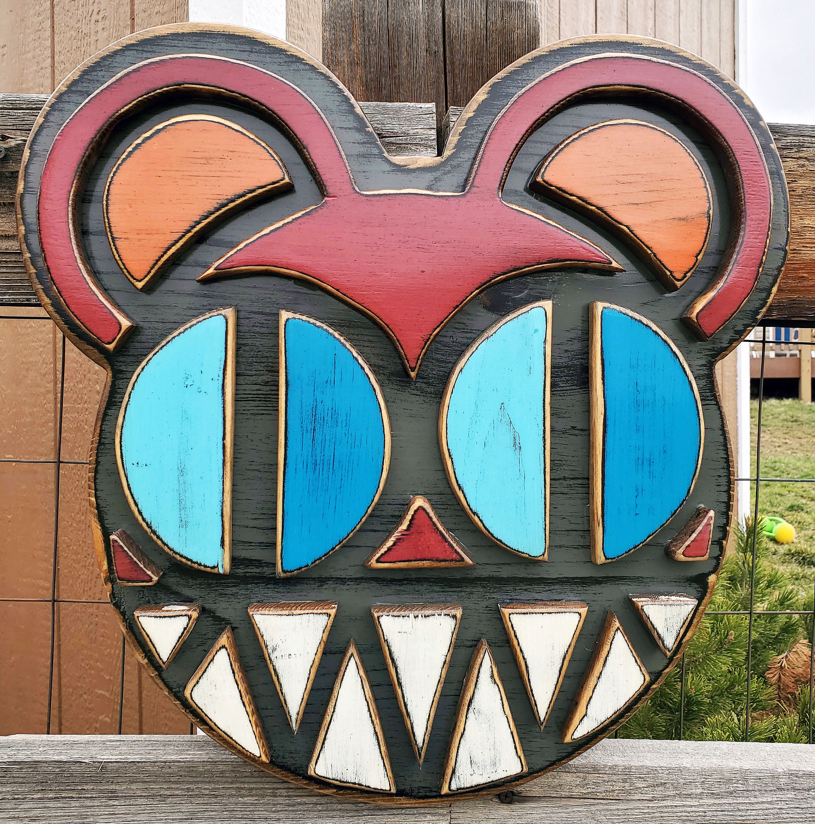 Decorative wooden wall art featuring Radiohead's Modified Bear logo on a wooden fence outdoors.