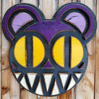 Decorative wooden wall art featuring Radiohead's Modified Bear logo on a wooden fence outdoors.