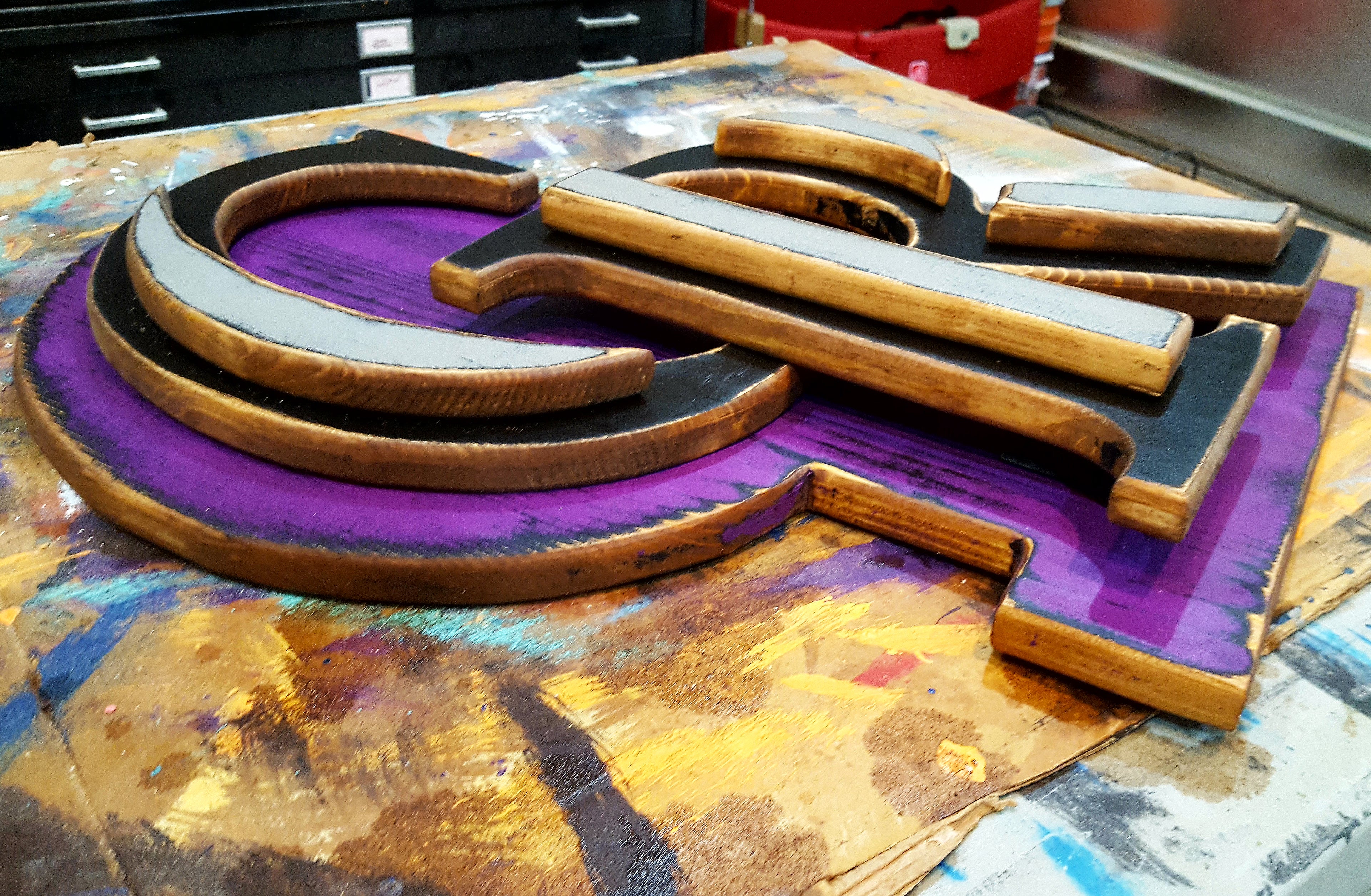 A top-down side view of the wooden layers of a Colorado Rockies art piece with various items in a garage making up the background