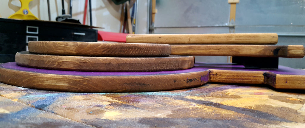 A side view of the wooden layers of a Colorado Rockies art piece with various items in a garage making up the background